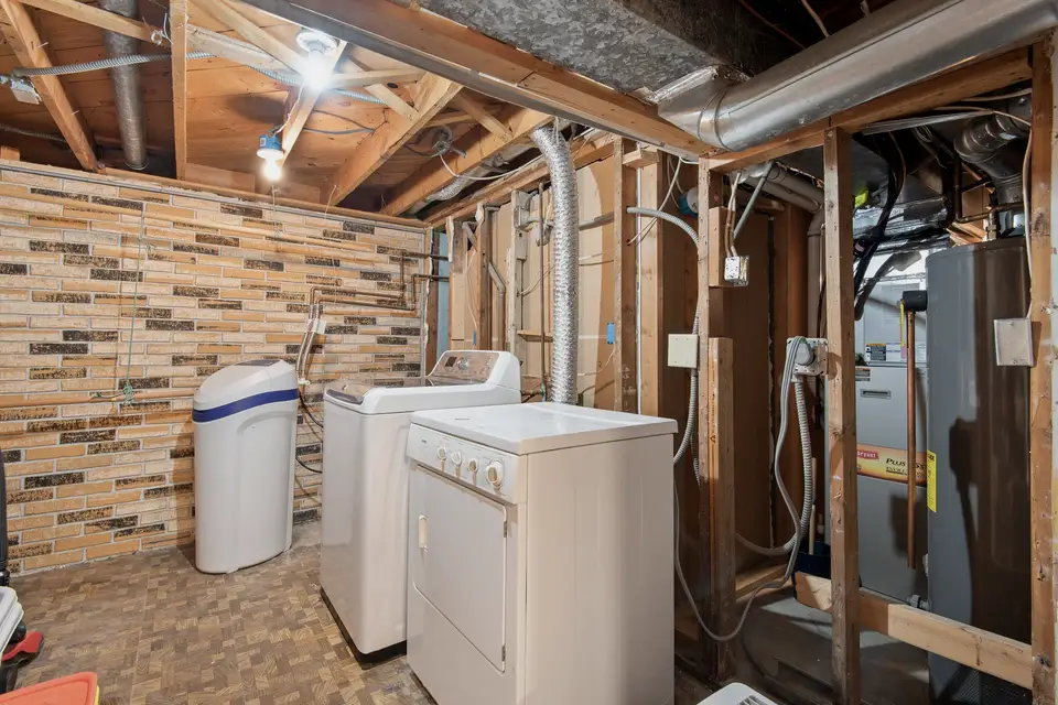 Unfinished basement with the water heater and laundry plumbing exposed