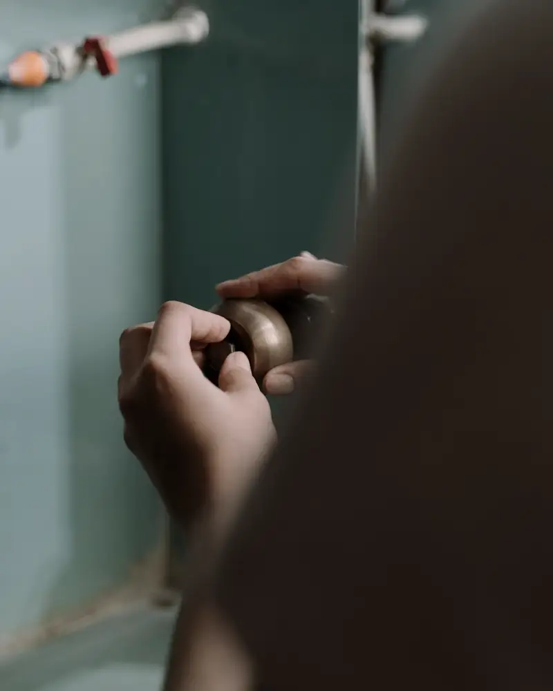 Hands adjusting the trap under a kitchen sink