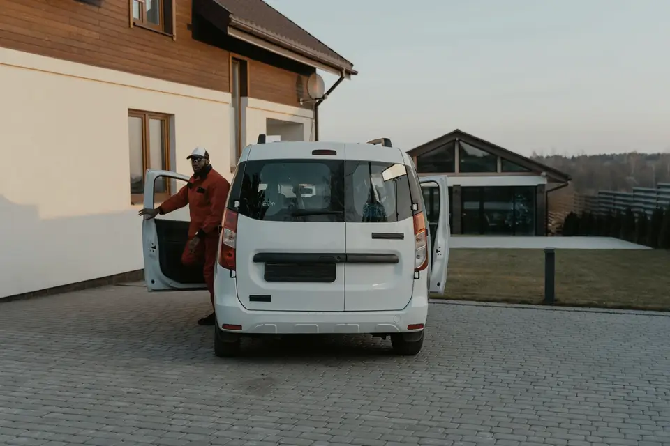 Worker in uniform stepping out of a white van in a residential driveway
